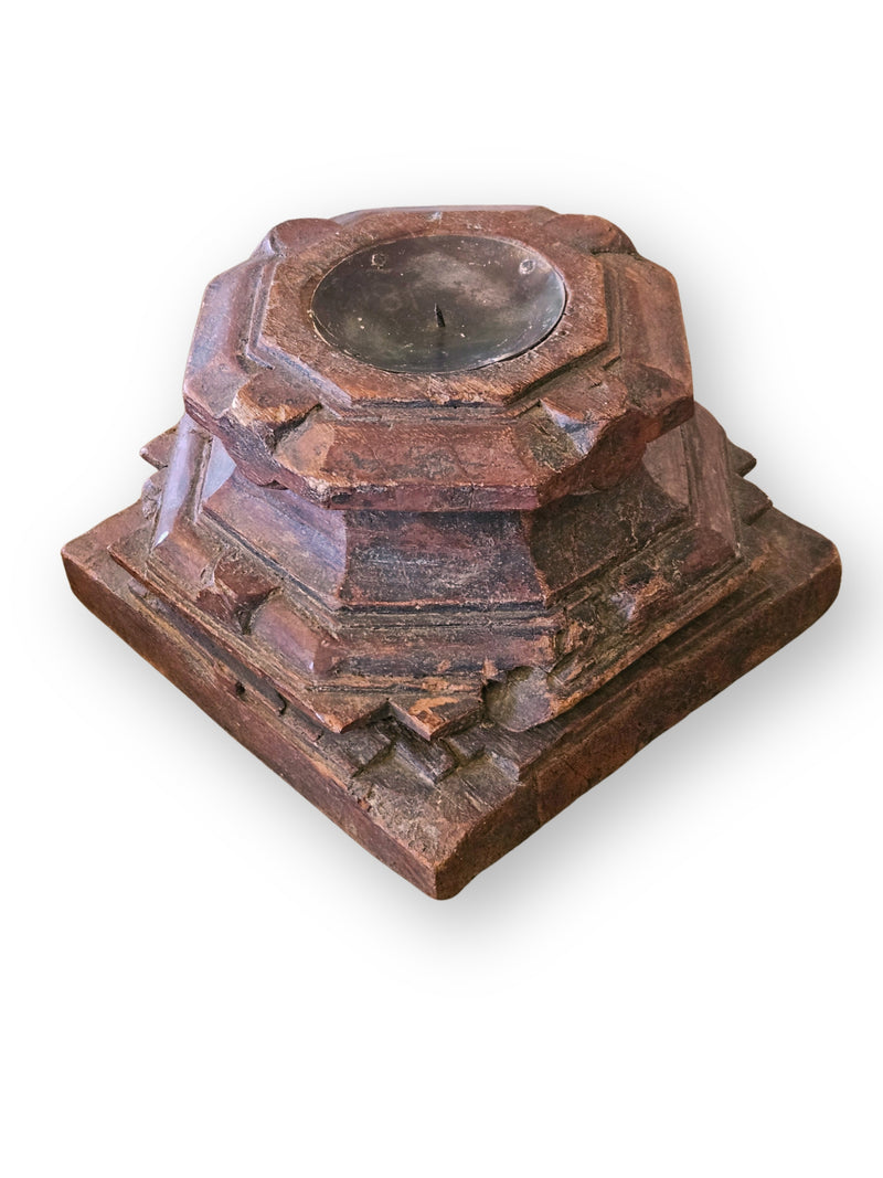 A rustic carved wooden candle holder with a tiered square base and a circular top insert, shown on a plain white background.