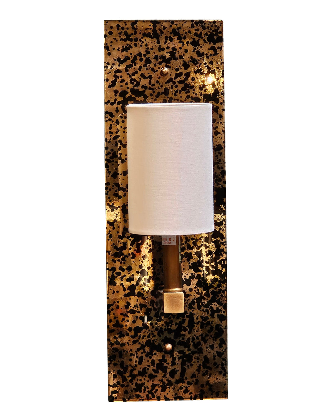 A modern wall sconce light fixture featuring a vertical rectangular backplate with a black and gold speckled pattern, a white cylindrical shade, and a metallic gold-finished stem.