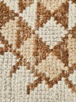 Close-up of a textured woven rug with a geometric star pattern in brown and cream.
